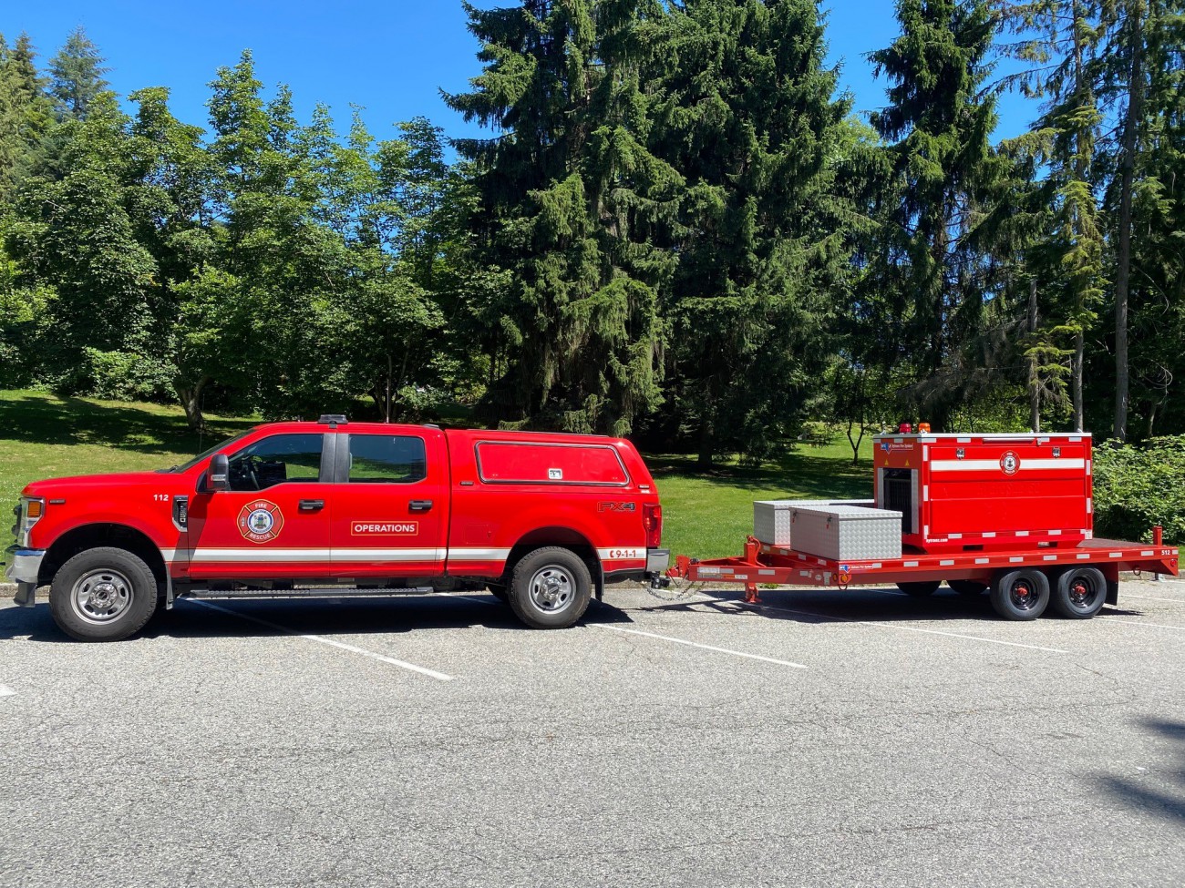 A red District of North Vancouver Fire Rescue Services pickup truck with a trailer that is loaded with a HydroSub-60 submersible pump used for access water from an open source such as the ocean or a river. 