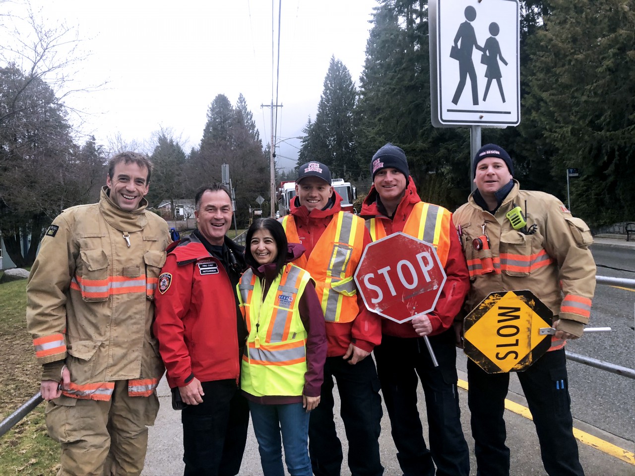 A group of smiling DNVFRS members, with one holding a stop sign.