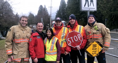 A group of smiling DNVFRS members, with one holding a stop sign.