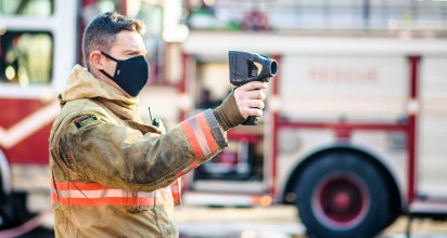 A firefighter holds up a thermal imaging device.