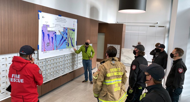 Group of firefighters look at map on wall.