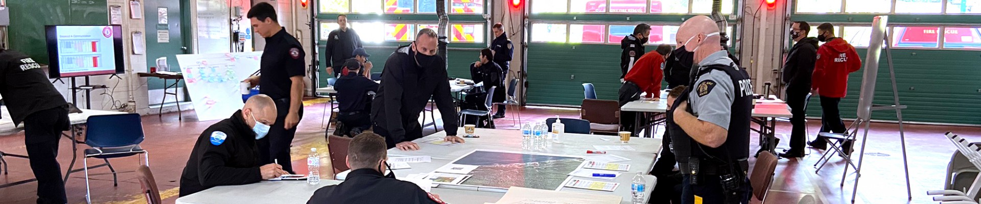 A group of DNVFRS personnel and RCMP around a table looking at a map.