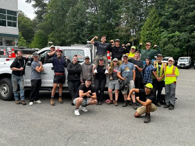 A group of smiling DNV Parks horticulturalists smile and make flexing gestures.