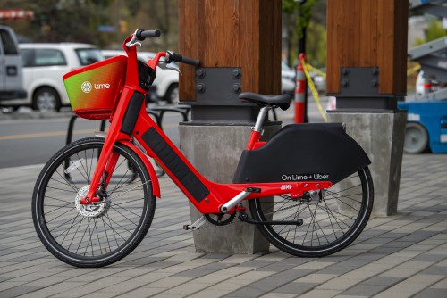 A red e-bike parked against a cement and wood pole.