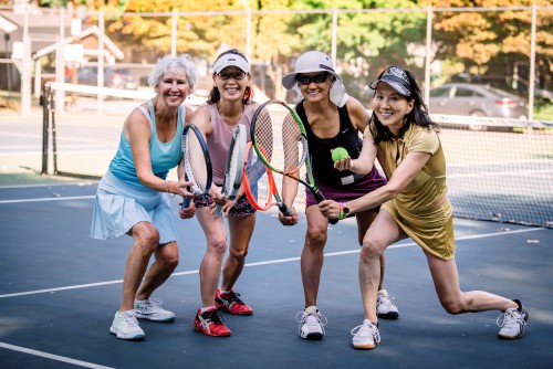 four ladies posing with tennis rackets