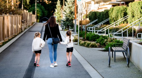 A mother walks down a path with her two young daughters.