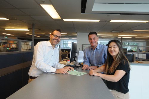 Three City Hall staff members smile at a service desk.