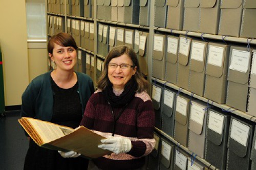 Two archive staff members standing in front of a book case